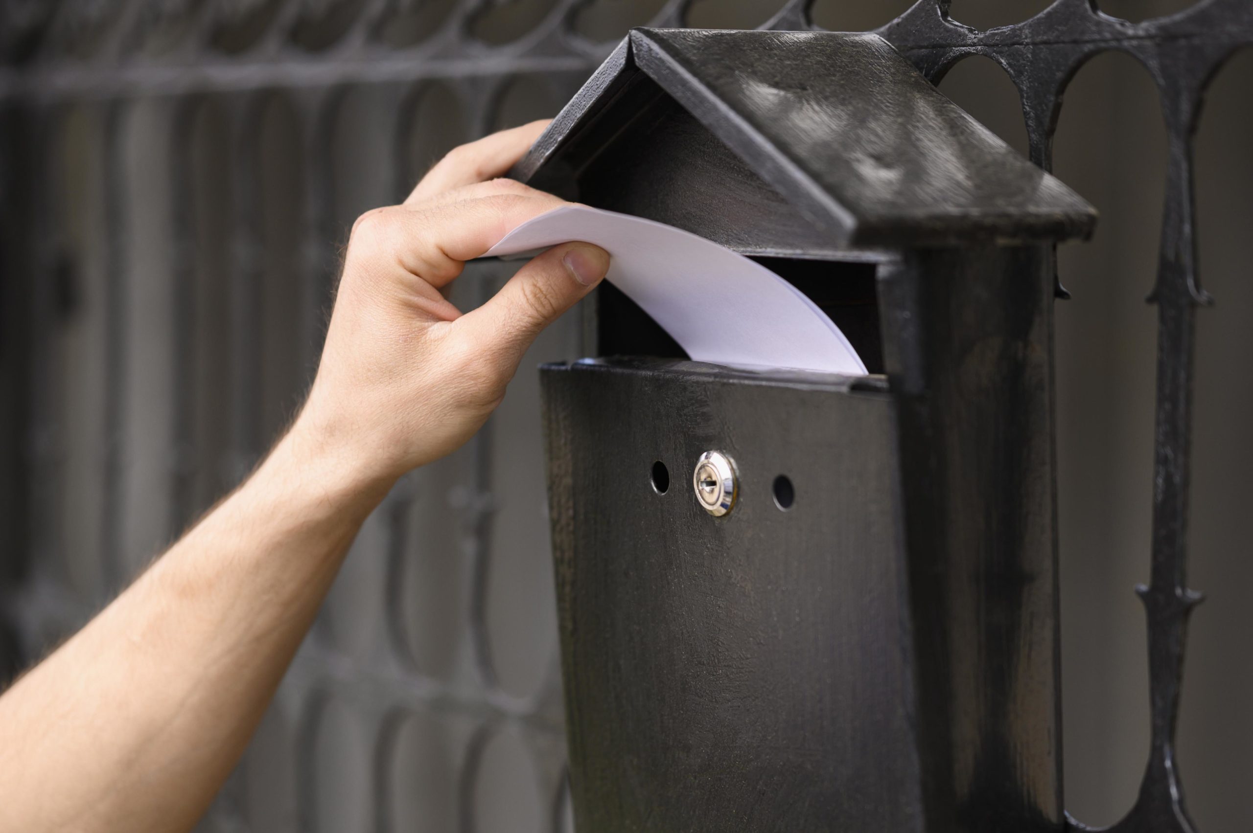 close-up-delivery-man-dropping-envelope-mailbox