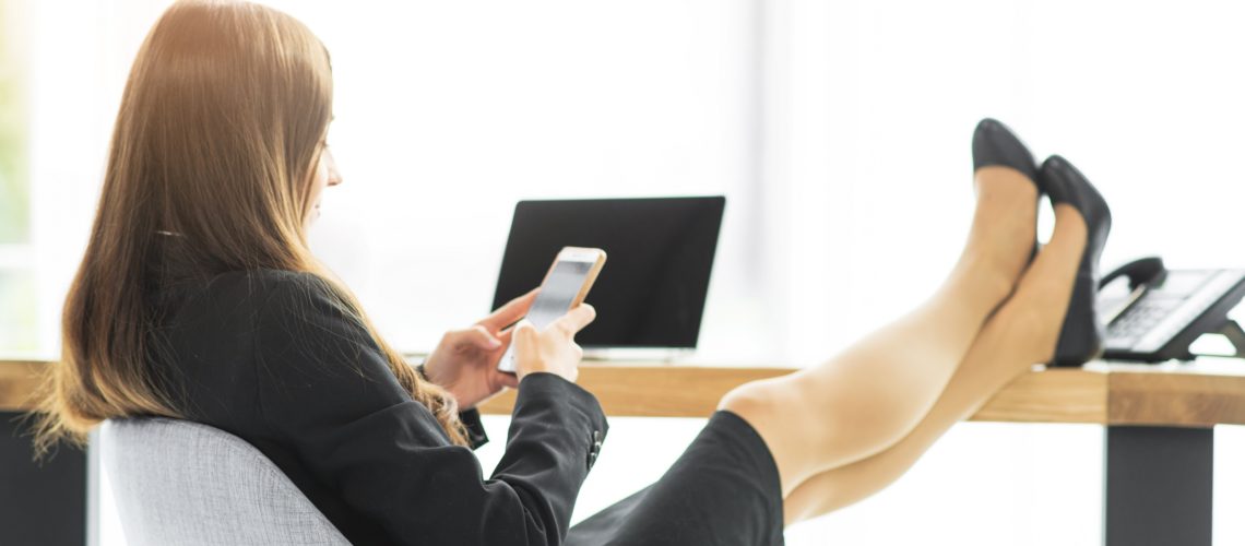 businesswoman-relaxing-at-desk-using-smartphone-in-the-office