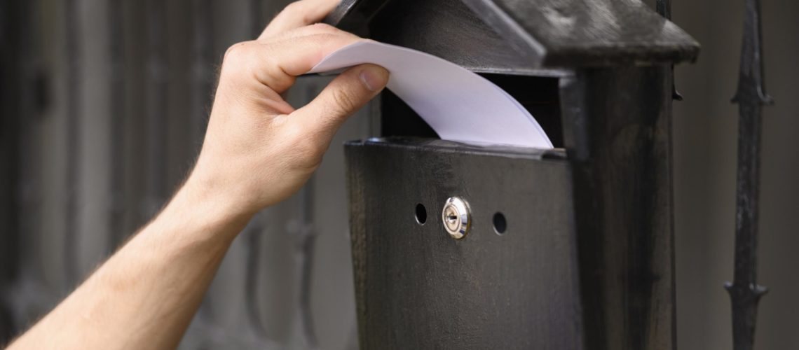 close-up-delivery-man-dropping-envelope-mailbox
